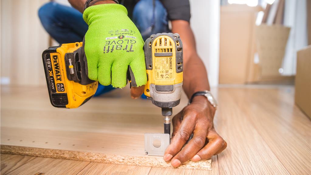 Person Using Dewalt Cordless Impact Driver on Brown Board