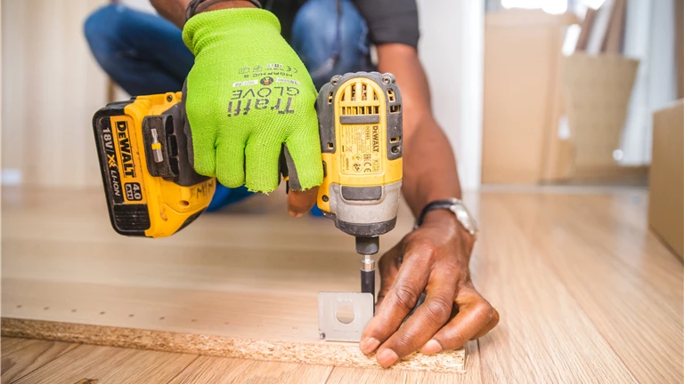 Person Using Dewalt Cordless Impact Driver on Brown Board