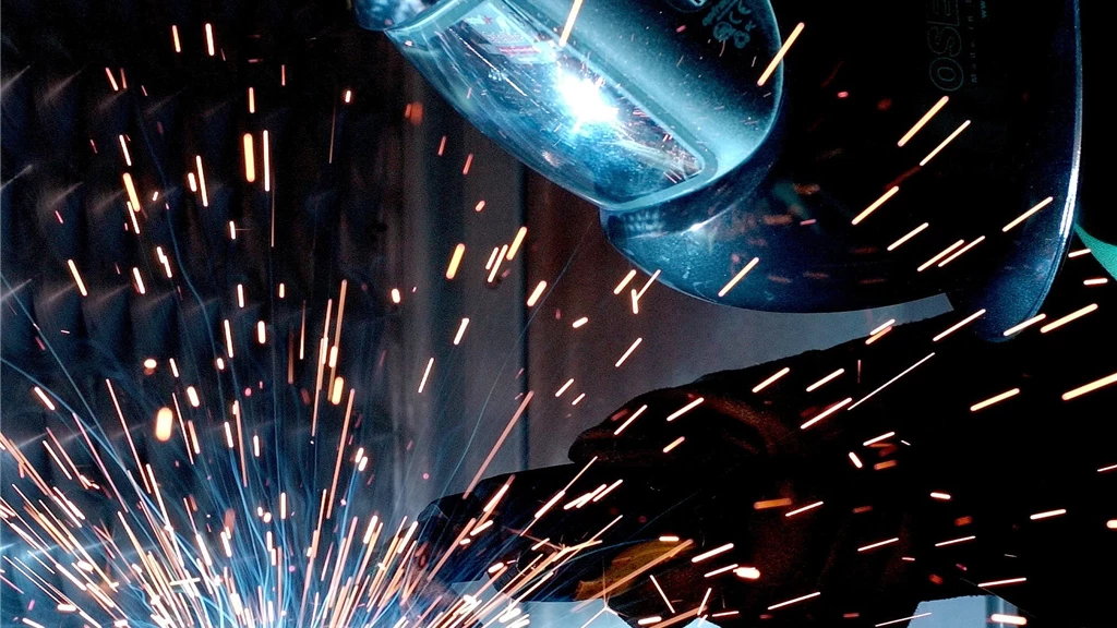 Person in Welding Mask While Welding a Metal Bar